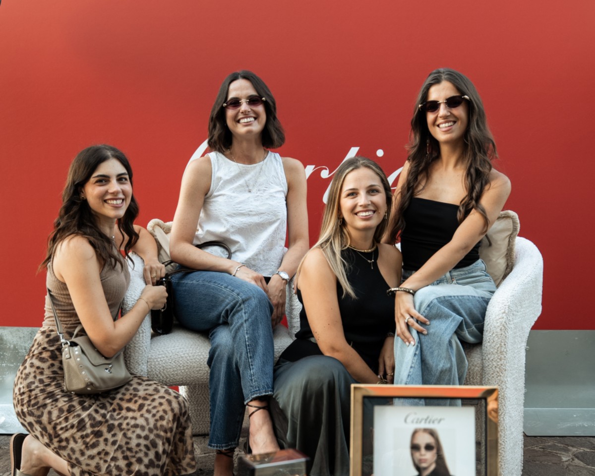 Quattro ragazze sorridenti sedute davanti alla parete rossa Cartier durante l evento presso il centro Zuppardo Ottica
